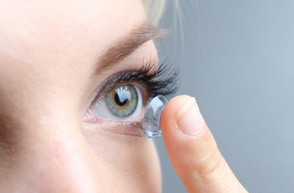 Close-up of a woman's left eye as she puts a contact lens in using her left hand