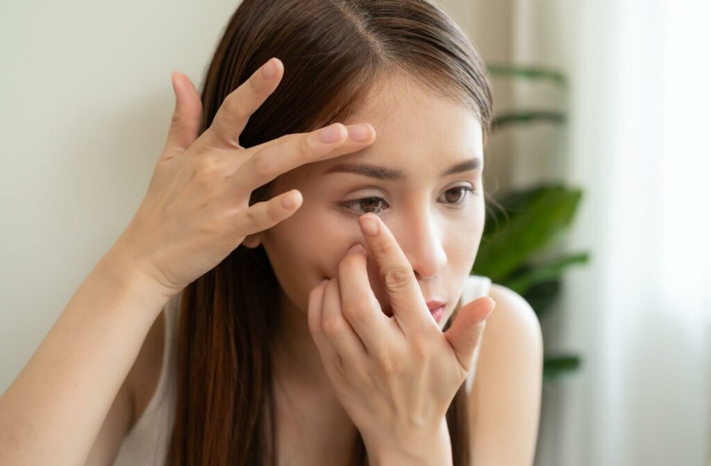 An adult places their freshly cleaned contact lens in their eye to enjoy frameless, clear vision.