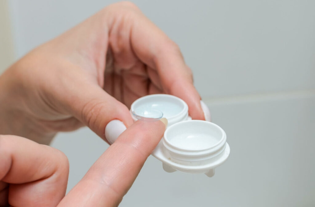 A close-up image of someone placing their contact lens into the proper contact lens storage container with the proper cleaning solution.