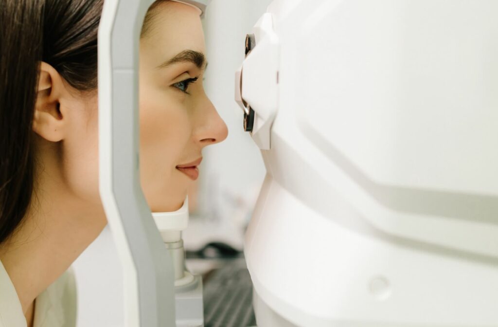 Young adult with long brown hair resting their chin and sitting with their eyes in front of a large white scanning machine.